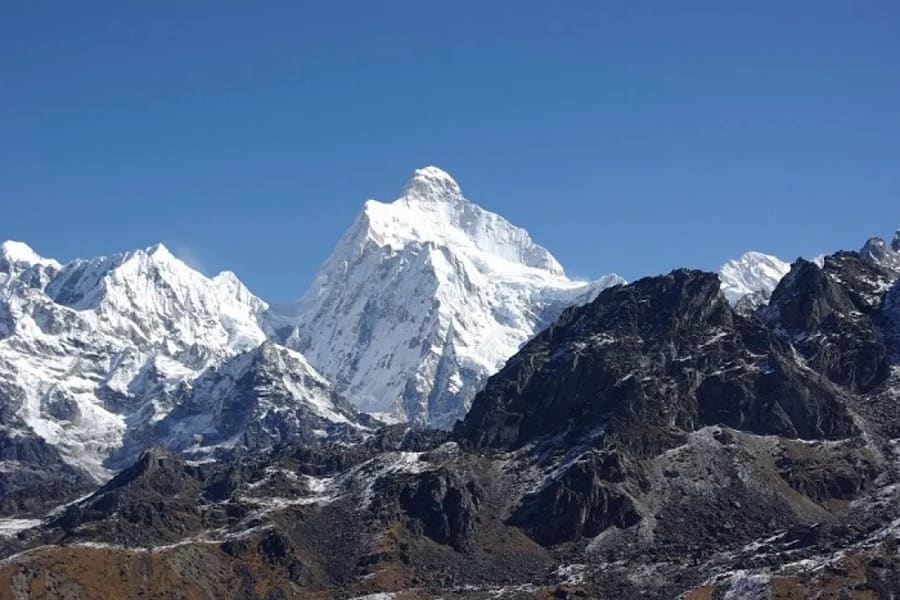 The snow-capped Kanchenjunga massif rising above dark rocky ridges