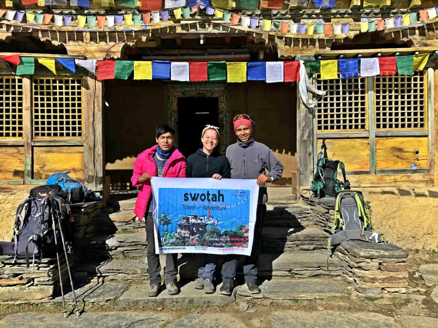 A Swotah guide and trekker holding a banner at a Manaslu teahouse