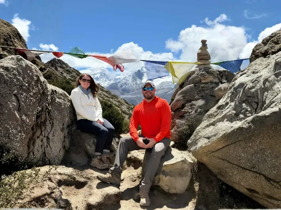 Trekkers resting under prayer flags on the Everest Base Camp trail with Ama Dablam behind, Khumbu, Nepal