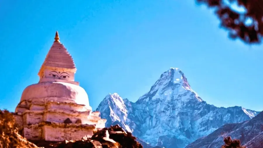 A white Buddhist stupa beside Ama Dablam at dusk in the Everest region